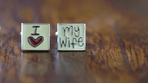Свадебные кольца и запонки на деревянном столе — стоковое видео