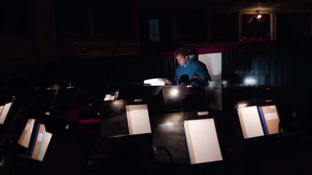 Dirigent in een orkestbak bestudeert bladmuziek — Stockvideo