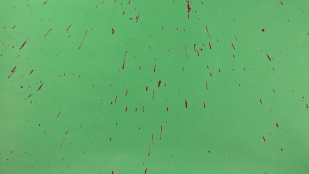 Κόκκινο μελάνι πασπαλίζονται πάνω από την πράσινη οθόνη φόντου — Αρχείο Βίντεο