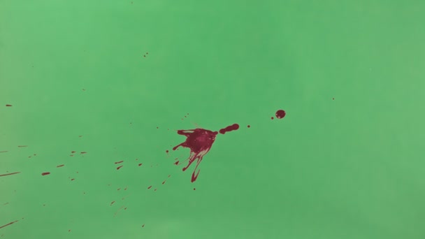 Красные чернила брызги на зеленом фоне экрана — стоковое видео