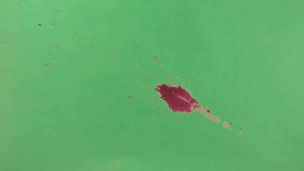Éclaboussure d'encre rouge sur fond d'écran vert 