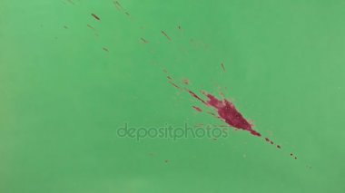 Kırmızı mürekkep sıçramak yeşil ekran arka planı üzerinde