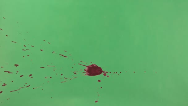 Rode inkt Splatter Over groene schermachtergrond — Stockvideo
