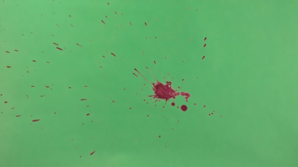 Éclaboussure d'encre rouge sur fond d'écran vert 