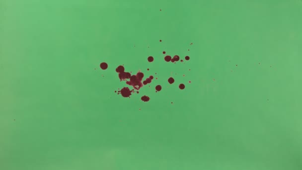 Salpicadura de tinta roja sobre fondo de pantalla verde — Vídeos de Stock