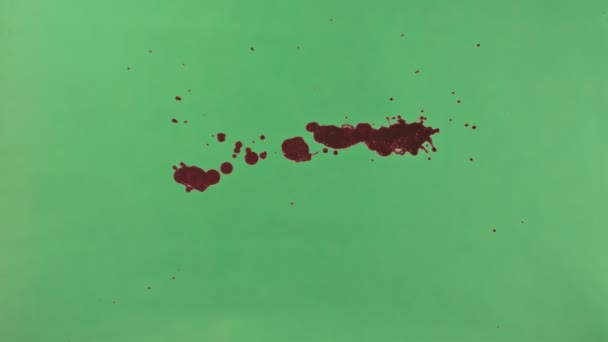 Mancha de tinta vermelha sobre fundo de tela verde — Vídeo de Stock