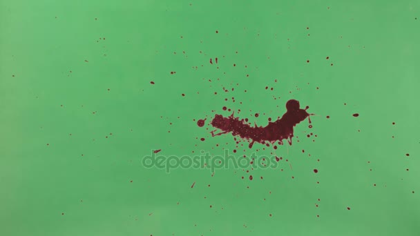 Mancha de tinta vermelha sobre fundo de tela verde — Vídeo de Stock