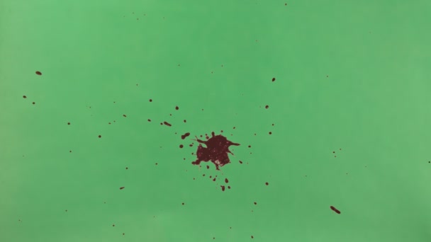 Κόκκινο μελάνι πιτσιλίσματα πάνω από την πράσινη οθόνη φόντου — Αρχείο Βίντεο