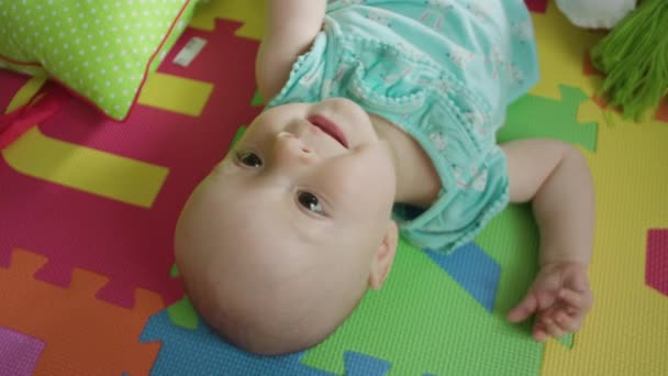 Pequeno bebê deitado em uma roupa de cama colorida — Vídeo de Stock