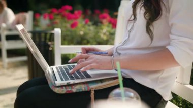 Bayan parkta bankta oturmuş ve dizüstü bilgisayar kullanarak