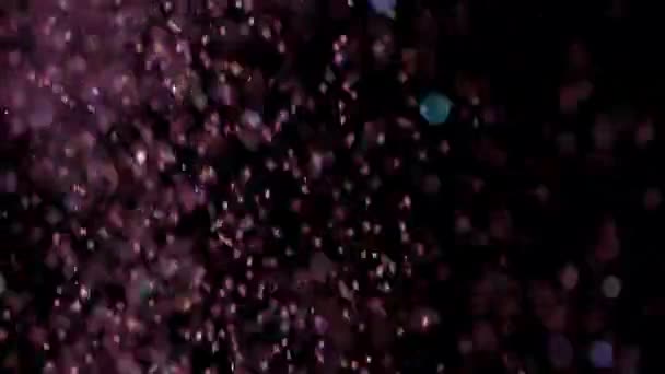 Paillettes réalistes explosant sur fond noir .