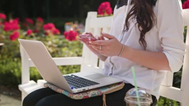 Bayan parkta oturan ve Laptop ve telefon kullanma