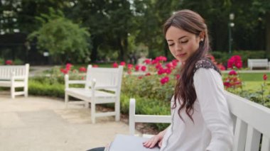 Bayan parkta bankta oturmuş ve dizüstü bilgisayar kullanarak