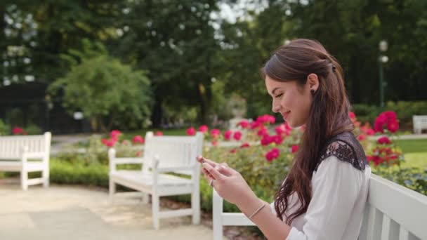 Dama en el parque usando un juego de teléfono — Vídeos de Stock