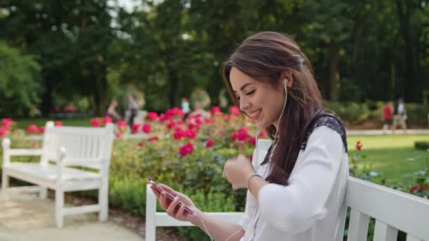 Lady i parken Lyssna på musik på telefonen — Stockvideo