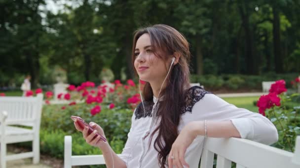 Lady in the Park escuchando música por teléfono — Vídeo de stock