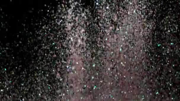 Paillettes réalistes explosant sur fond noir .