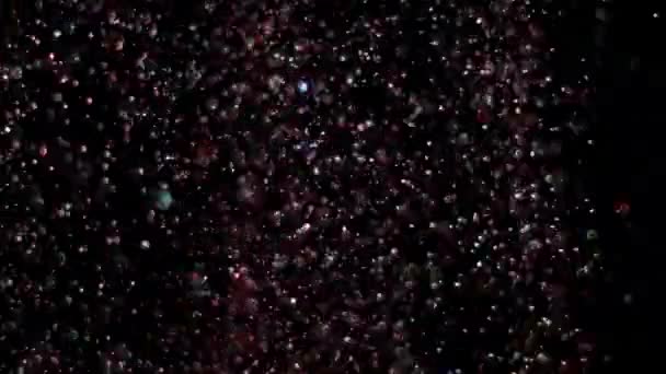 Paillettes réalistes explosant sur fond noir .