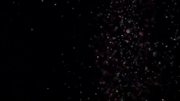 Paillettes réalistes explosant sur fond noir .