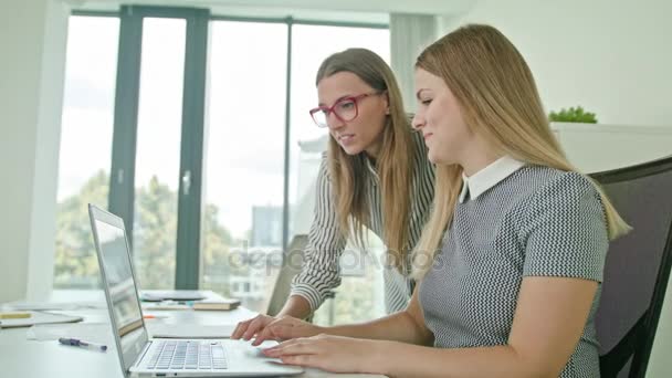 Dos mujeres discutiendo ideas usando el ordenador portátil — Vídeo de stock