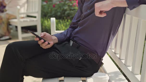 Молодой человек в парке с помощью телефона — стоковое видео