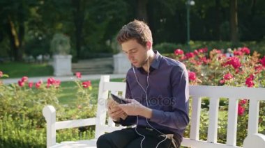 Genç adam parkta bir telefonu kullanarak ve içme