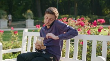 Genç adam parkta bir telefonu kullanarak ve içme