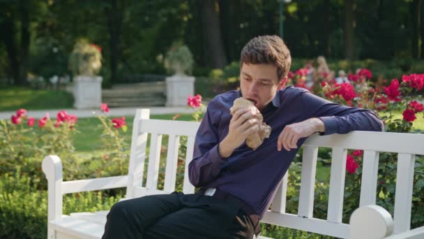 Jonge Man met een Snack in het Park — Stockvideo