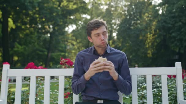 Junger Mann bei einem Imbiss im Park — Stockvideo
