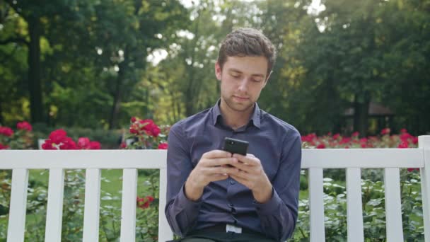 Ung Man i parken med hjälp av en telefon — Stockvideo