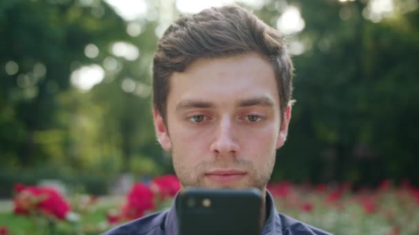 Jovem no parque usando um telefone — Vídeo de Stock