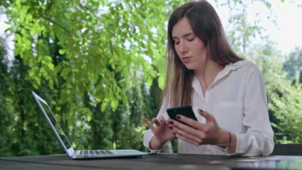 Mujer de negocios usando un ordenador portátil y un teléfono — Vídeos de Stock