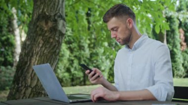 Parkta bir telefonu kullanarak bir genç adam