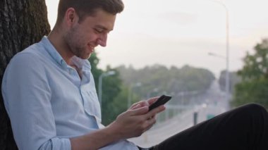 Genç bir adam açık havada bir cep telefonu kullanarak