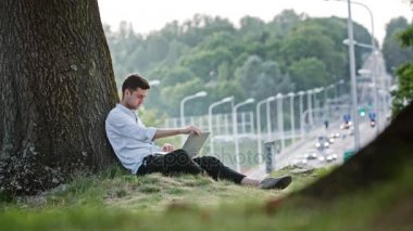 genç bir adam bir dizüstü bilgisayar açık havada kullanma