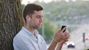 Genç bir adam açık havada bir cep telefonu kullanarak