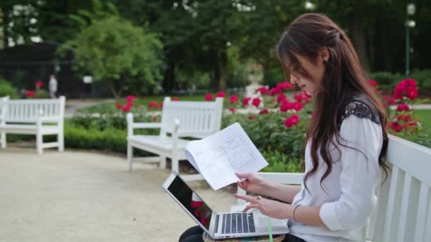 Леді, сидячи в парку, використовуючи ноутбук. Введення даних — стокове відео