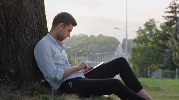 Um jovem usando uma tabuleta ao ar livre — Vídeo de Stock