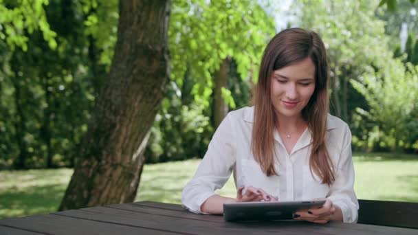 Jeune femme utilisant un iPad dans le parc — Video