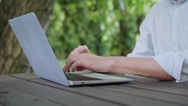 Мужские руки с помощью ноутбука в парке — стоковое видео