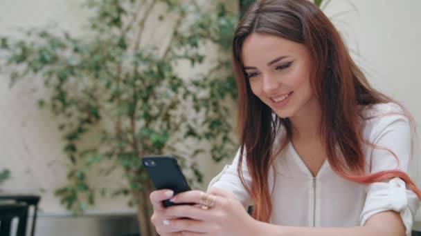 Mooi meisje met behulp van een mobiele telefoon op de kamer — Stockvideo