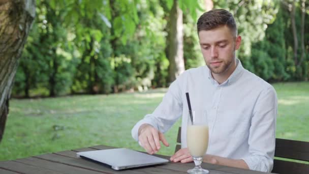 Een jonge Man Milkshake drinken in het Park — Stockvideo