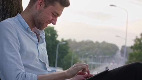 Un joven usando una tableta al aire libre — Vídeos de Stock