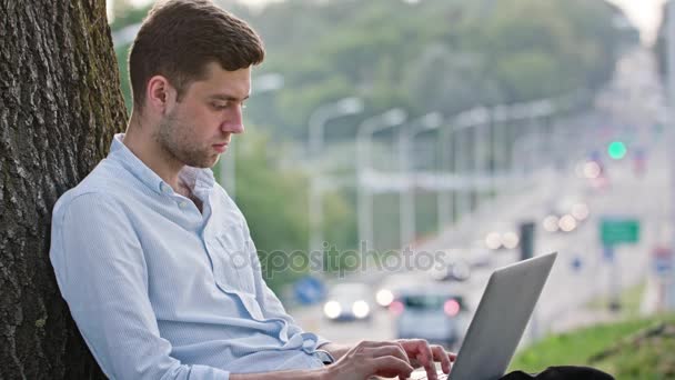 Um jovem usando um laptop ao ar livre — Vídeo de Stock