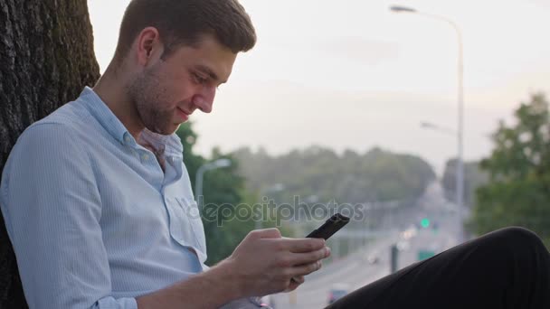 Ein junger Mann mit einem Handy im Freien — Stockvideo