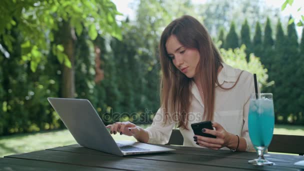 Mujer de negocios usando un ordenador portátil y un teléfono — Vídeos de Stock