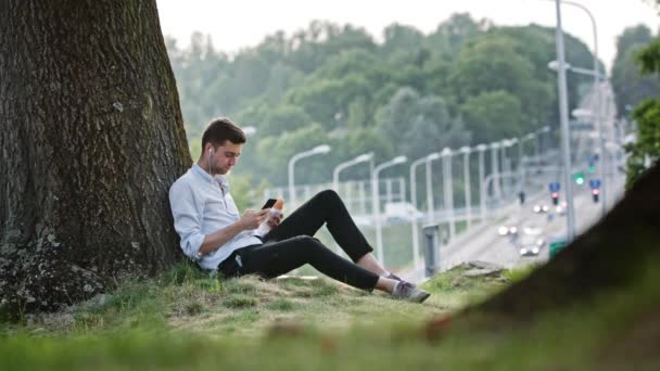 Un joven usando un móvil al aire libre — Vídeos de Stock