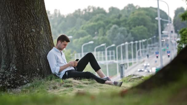 Un joven usando un móvil al aire libre — Vídeo de stock