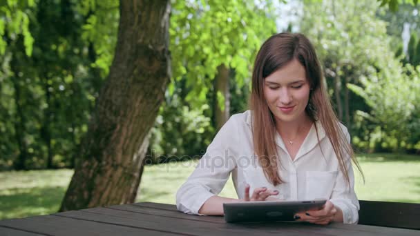 Девушка, использующая iPad в парке — стоковое видео