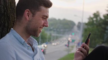 Genç bir adam açık havada bir cep telefonu kullanarak